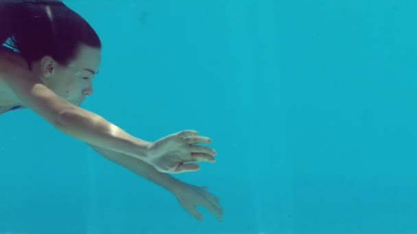 Brunette woman swimming underwater in blue bathing suit — Stock Video