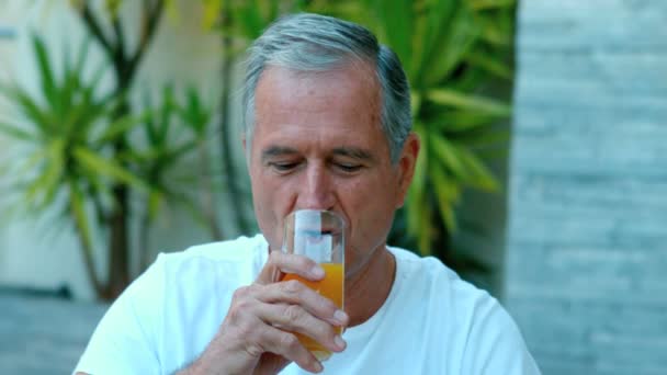 Homem aposentado bebendo suco de laranja lá fora — Vídeo de Stock