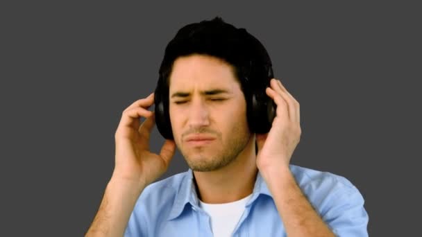 Člověk poslouchal hudbu se sluchátky na šedém pozadí — Stock video