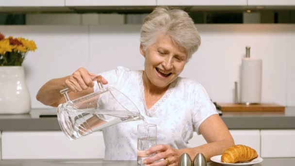 Femme âgée versant un verre d'eau pour le petit déjeuner — Video