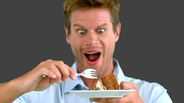 Gri ekran üzerinde bir pasta yemek için çekici bir adam — Stok video