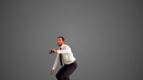 Businessman leaping and taking self portrait on grey background — Stock Video