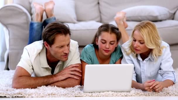 Parents and daughter happily using laptop on floor — Stock Video