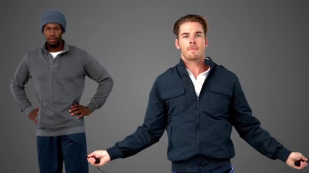 男と彼のコーチの横にある灰色の背景上の縄跳びのジャンプ — ストック動画