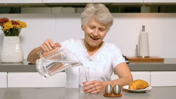Счастливая женщина наливает стакан воды на завтрак — стоковое видео