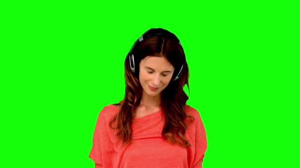 Mujer con auriculares escuchando música en pantalla verde — Vídeo de stock