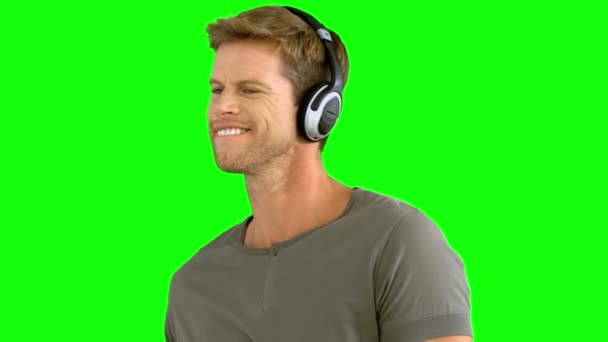 Hombre atractivo con auriculares escuchando música en pantalla verde — Vídeos de Stock