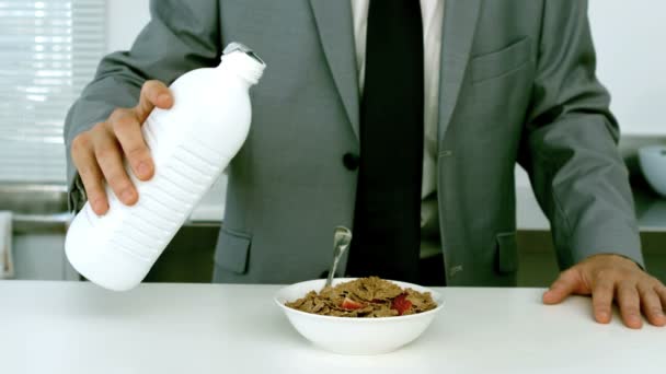 Хорошо одетый бизнесмен наливает молоко в свои хлопья — стоковое видео