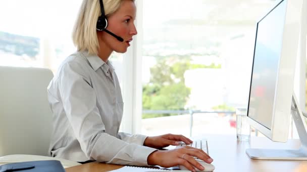 Mujer de negocios hablando en auriculares y mecanografía — Vídeos de Stock