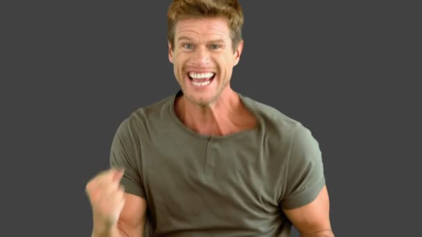 身振りで示すと、灰色の画面に自分の幸福を示す魅力的な男性 — ストック動画