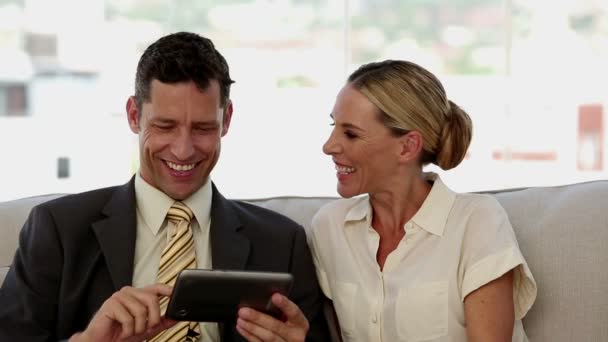 Colegas riendo juntos mientras trabajan en una tableta — Vídeos de Stock