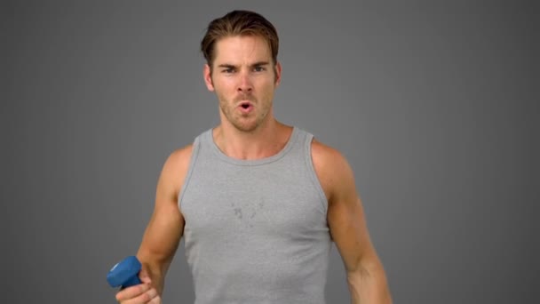 Man exercising with dumbbell on grey background — Stock Video