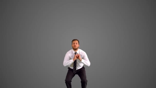 Businessman jumping and stretching towards the camera on grey background — Stock Video