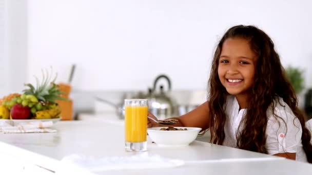 Klein meisje glimlachen in de camera bij het ontbijt — Stockvideo