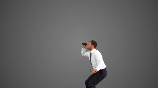 Businessman leaping and holding binoculars on grey background — Stock Video