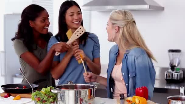 Laughing friends singing into a wooden spoon while cooking — Stock Video