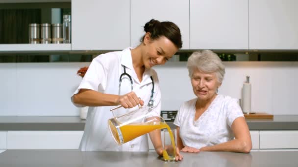 Home nurse pouring juice for patient in kitchen — Stock Video