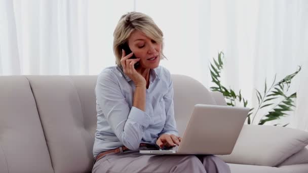 Mujer en el teléfono usando el ordenador portátil — Vídeo de stock