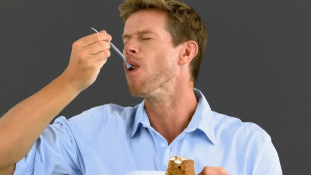 Чоловік смакує смачний торт на сірому екрані — стокове відео