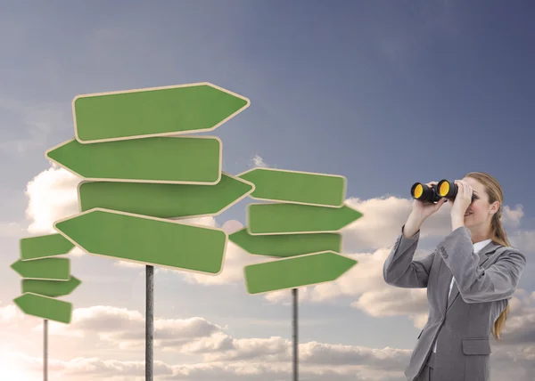 Businesswoman looking at empty signposts with binoculars — Stockfoto