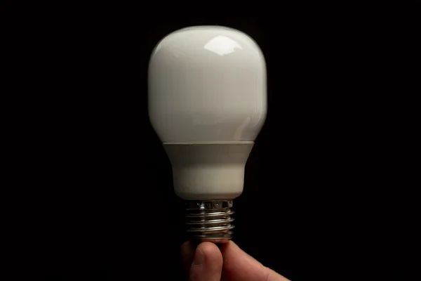 Man holding economic light bulb in his fingertips close up — Stock Photo, Image
