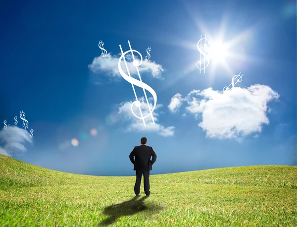 Businessman looking up at dollar signs in the sky — Stock Photo, Image