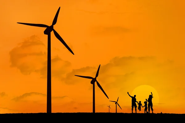 Turbinas eólicas e família pulando com um pôr do sol — Fotografia de Stock