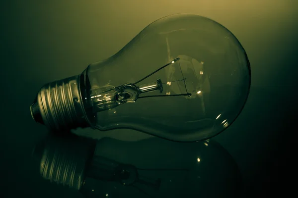 Clear light bulb in green light — Stock Photo, Image