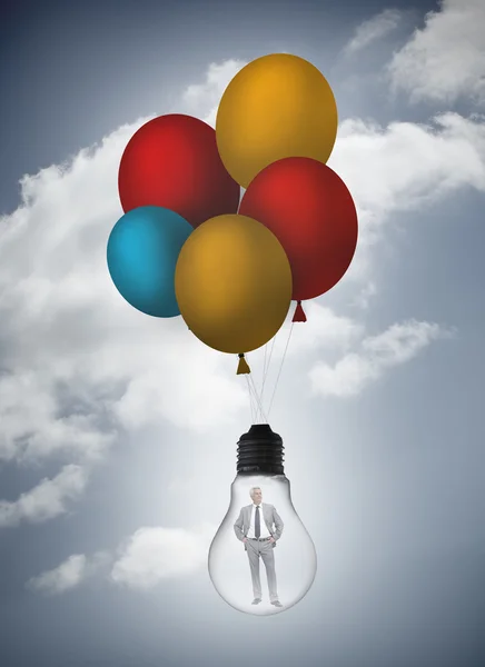 Businessman inside light bulb held by balloons — Stock Photo, Image