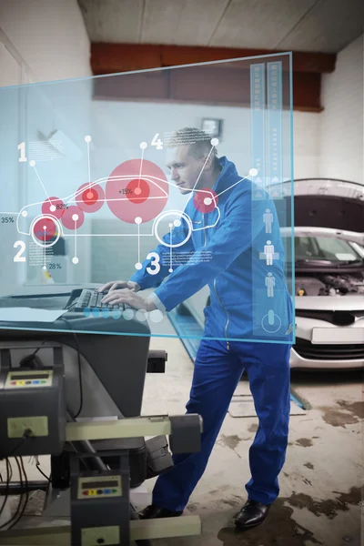 Mechanic typing while consulting futuristic interface with car d — Stock Photo, Image