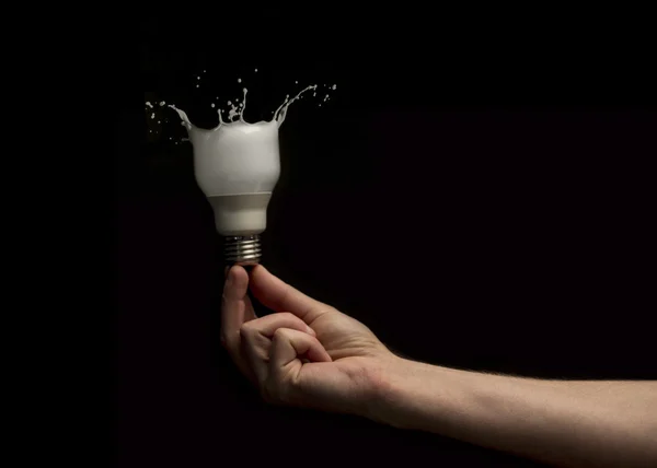 Hand holding light bulb turning to paint — Stock Photo, Image