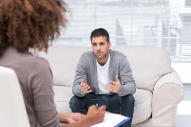 Depressed man speaking to a therapist clipart
