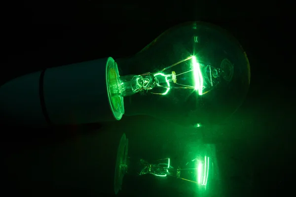 Green light bulb turned over on black background — Stock Photo, Image