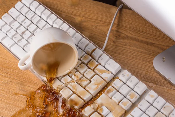 Xícara de chá derramando sobre um teclado — Fotografia de Stock