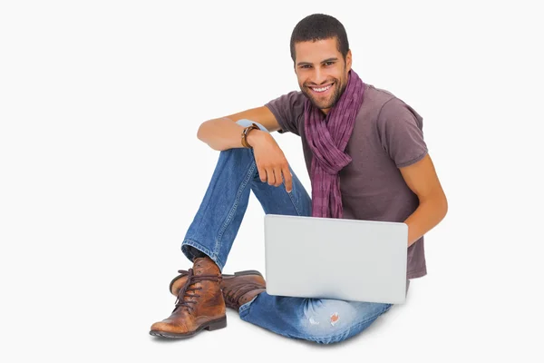 Happy man sitting on floor using laptop looking at camera — Stock Photo, Image