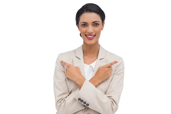 Mujer de negocios sonriente con los brazos cruzados y los dedos señalando — Foto de Stock