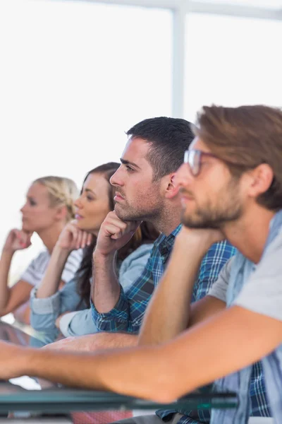 Creative team sitting in a line listening to something — Stock Photo, Image