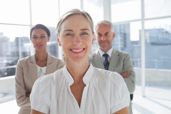 Smiling businesswoman standing in front of colleagues — Stock Photo, Image