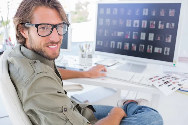 Editor di foto girando e sorridendo alla sua scrivania — Foto Stock