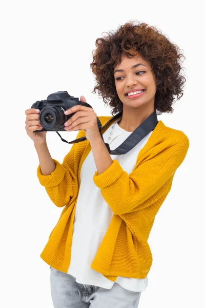 Smiling girl holding digital camera and looking at it — Stock Photo, Image