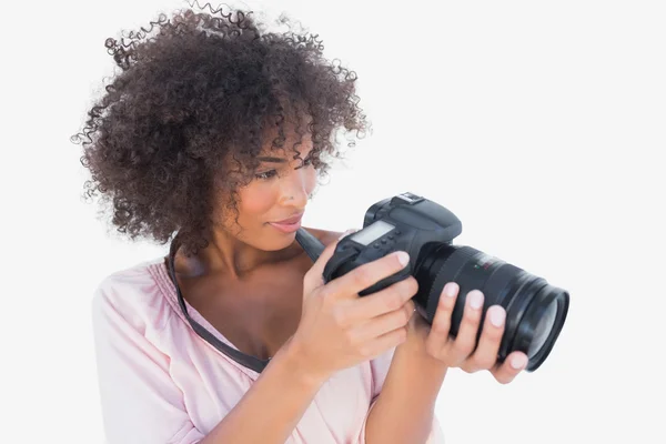 Femme souriante regardant appareil photo numérique — Photo