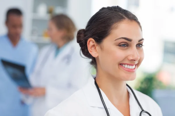 Smiling doctor standing in front of a medical team — Stock Photo, Image