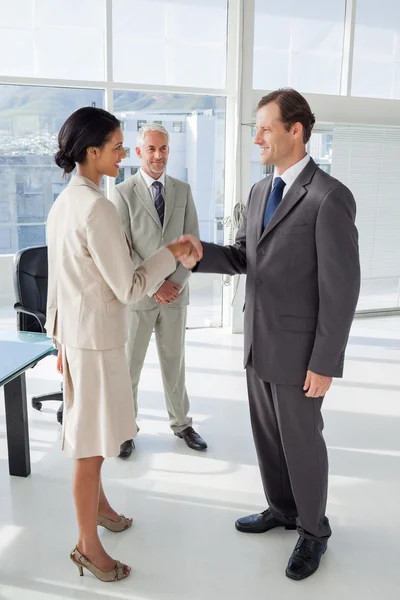 Two shaking their hands with colleague watching them — Stock Photo, Image