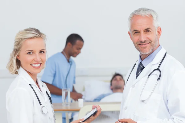 Médicos sonrientes de pie frente al paciente —  Fotos de Stock