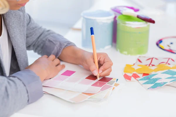 Pretty interior designer drawing on colour samples — Stock Photo, Image