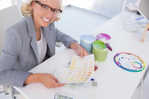 Loira sorridente designer de interiores segurando gráficos de cores — Fotografia de Stock