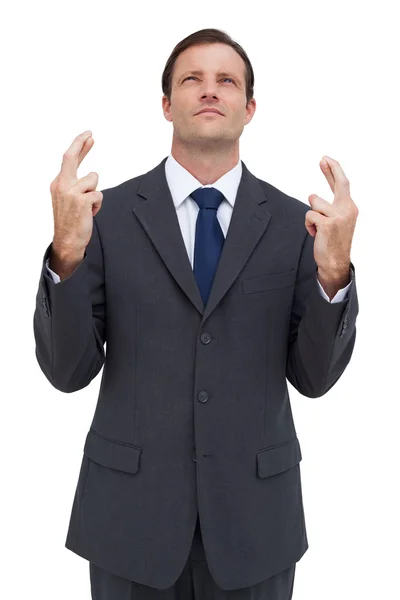 Serious businessman with fingers crossed is looking up — Stock Photo, Image