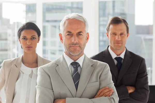 Hombre de negocios serio de pie con sus colegas detrás —  Fotos de Stock