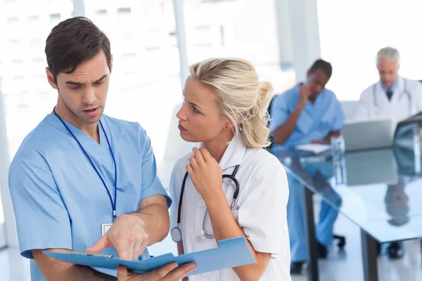 Two doctors talking about a blue file — Stock Photo, Image