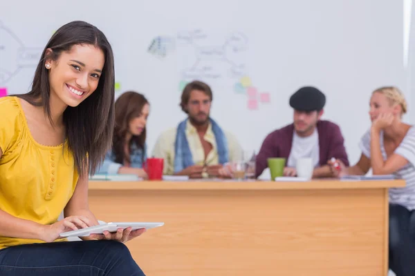 Prettty editor using tablet as team works behind her — Stock Photo, Image